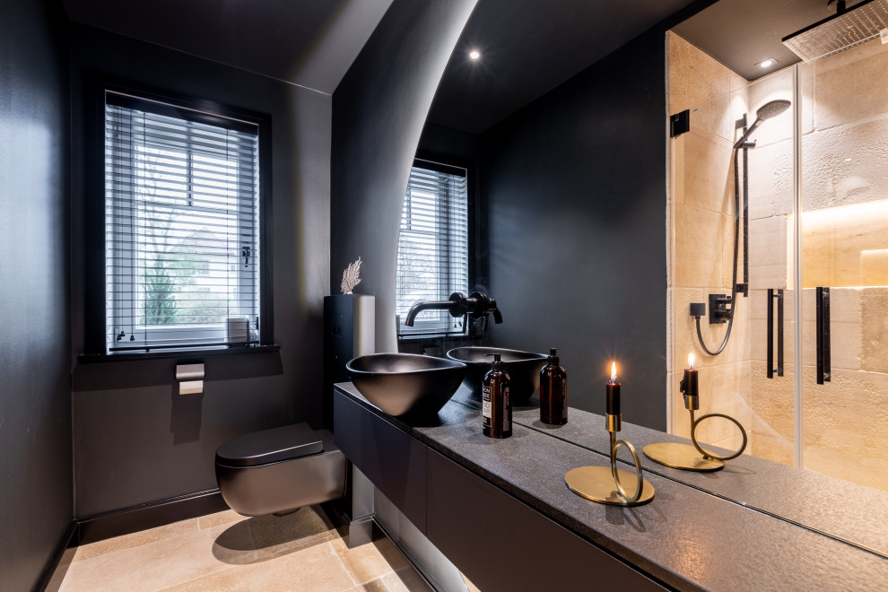 Exempel på ett litet modernt svart svart badrum, med släta luckor, svarta skåp, en kantlös dusch, en toalettstol med hel cisternkåpa, beige kakel, travertinkakel, svarta väggar, ett fristående handfat, bänkskiva i akrylsten och dusch med gångjärnsdörr