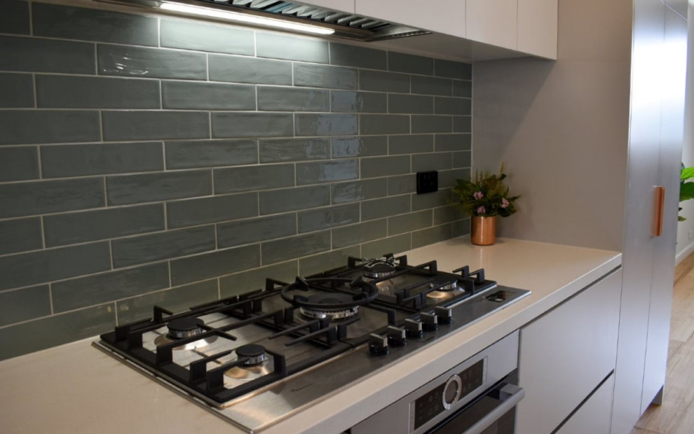 Design ideas for a mid-sized contemporary galley kitchen in Melbourne with a double-bowl sink, grey cabinets, quartz benchtops, green splashback, subway tile splashback, stainless steel appliances, light hardwood floors and with island.
