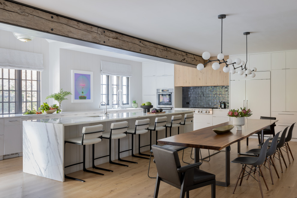 Design ideas for a large contemporary l-shaped open plan kitchen in Boston with an undermount sink, flat-panel cabinets, white cabinets, marble benchtops, blue splashback, glass tile splashback, panelled appliances, light hardwood floors, with island, white benchtop and exposed beam.