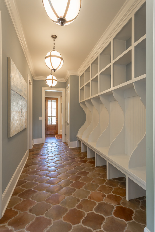 Design ideas for a mid-sized traditional mudroom in Other with grey walls, terra-cotta floors, a single front door, a medium wood front door and red floor.