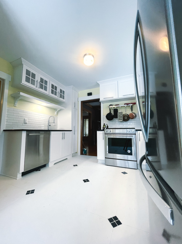 Mid-sized ceramic tile and white floor kitchen photo with an undermount sink, white cabinets, quartzite countertops, white backsplash, ceramic backsplash, stainless steel appliances, no island and black countertops