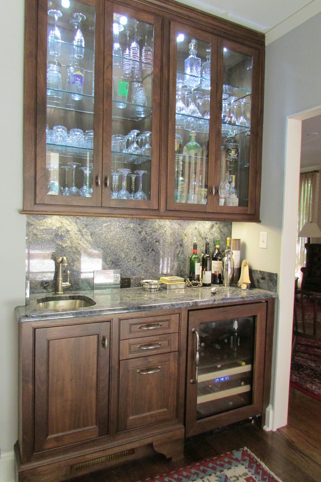 Inspiration for a small traditional single-wall wet bar in New Orleans with an undermount sink, glass-front cabinets, dark wood cabinets, quartz benchtops, grey splashback, stone slab splashback and dark hardwood floors.