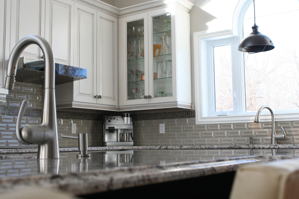Example of a huge transitional l-shaped medium tone wood floor and brown floor open concept kitchen design in Montreal with an undermount sink, glass-front cabinets, white cabinets, granite countertops, gray backsplash, ceramic backsplash, stainless steel appliances, an island and multicolored countertops