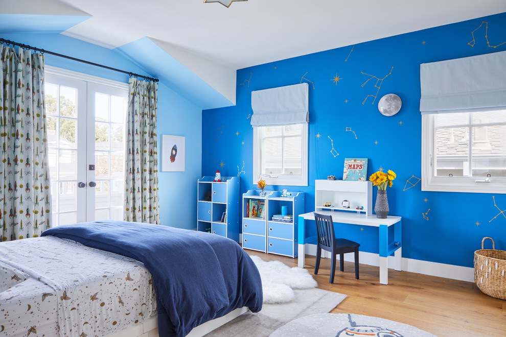 This is an example of a beach style kids' bedroom for kids 4-10 years old in Los Angeles with blue walls, light hardwood floors and beige floor.