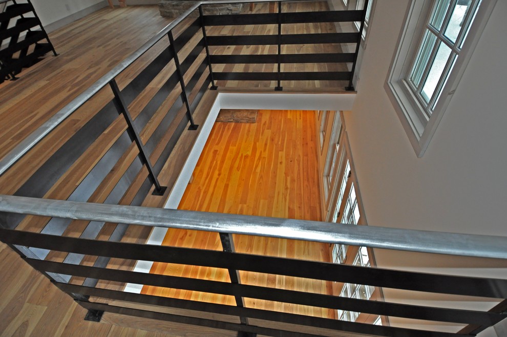 This is an example of a large transitional wood curved staircase in Boston with open risers and metal railing.