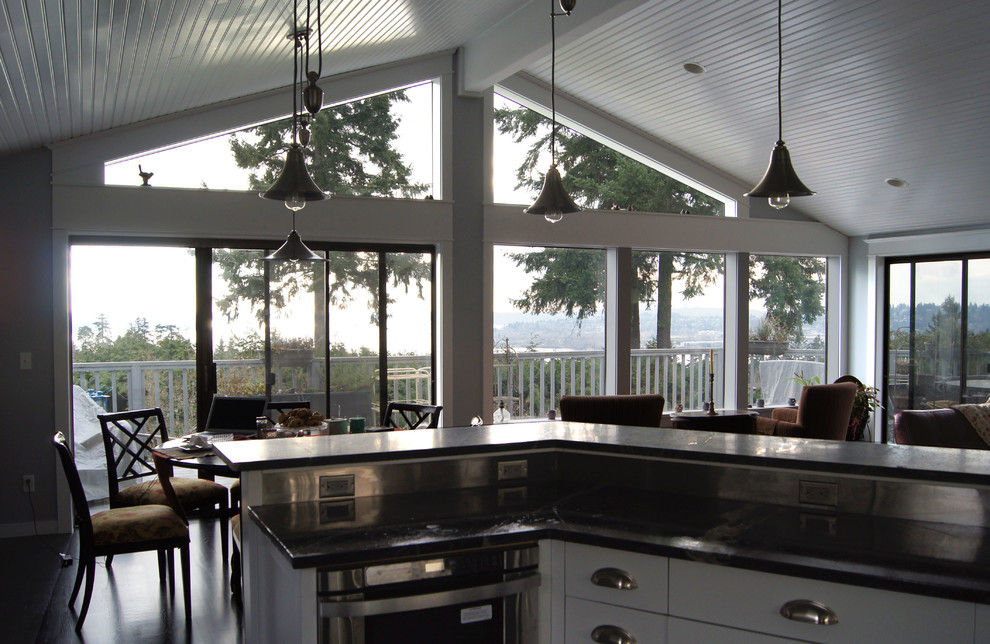 Design ideas for a large traditional l-shaped open plan kitchen in Seattle with white cabinets, with island, stainless steel appliances, dark hardwood floors, soapstone benchtops, shaker cabinets and a farmhouse sink.