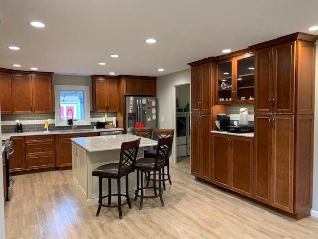 Eat-in kitchen - mid-sized transitional u-shaped vinyl floor and multicolored floor eat-in kitchen idea with a double-bowl sink, raised-panel cabinets, medium tone wood cabinets, granite countertops, gray backsplash, ceramic backsplash, stainless steel appliances, an island and gray countertops