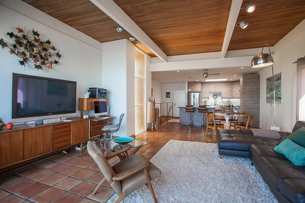 Photo of a mid-sized midcentury loft-style living room in Orange County with white walls, terra-cotta floors, a corner fireplace and a freestanding tv.
