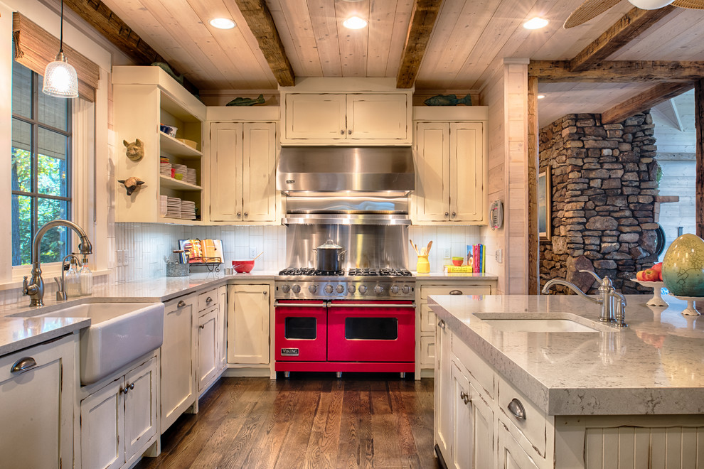 Design ideas for a mid-sized country l-shaped eat-in kitchen in Minneapolis with with island, a farmhouse sink, shaker cabinets, distressed cabinets, quartzite benchtops, white splashback, ceramic splashback, stainless steel appliances and medium hardwood floors.
