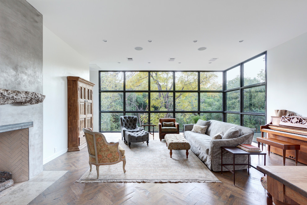 This is an example of a large contemporary open concept living room in Austin with white walls, medium hardwood floors, a standard fireplace, a plaster fireplace surround and no tv.