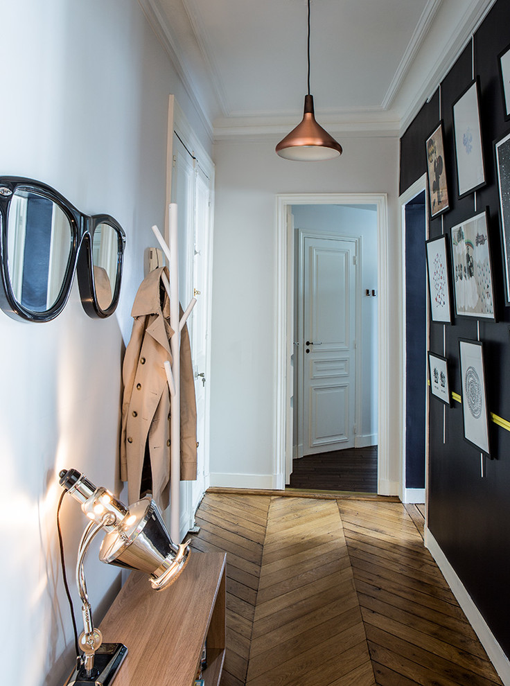 Photo of a mid-sized eclectic hallway in Paris with white walls and medium hardwood floors.