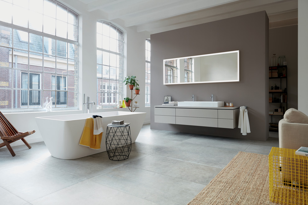 Photo of a large contemporary bathroom with grey cabinets, a freestanding tub and a trough sink.