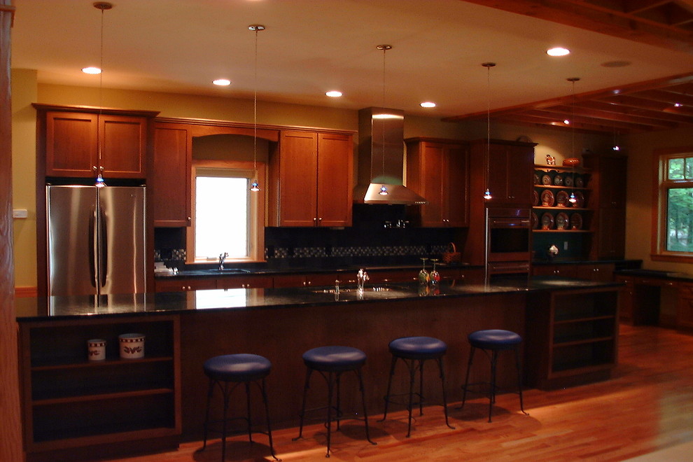 Large mountain style galley medium tone wood floor open concept kitchen photo with a double-bowl sink, medium tone wood cabinets, granite countertops, blue backsplash, ceramic backsplash, stainless steel appliances and a peninsula