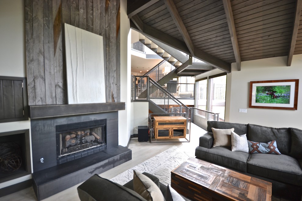 Inspiration for a large industrial open concept family room in Salt Lake City with white walls, a standard fireplace, a metal fireplace surround, no tv, beige floor and light hardwood floors.