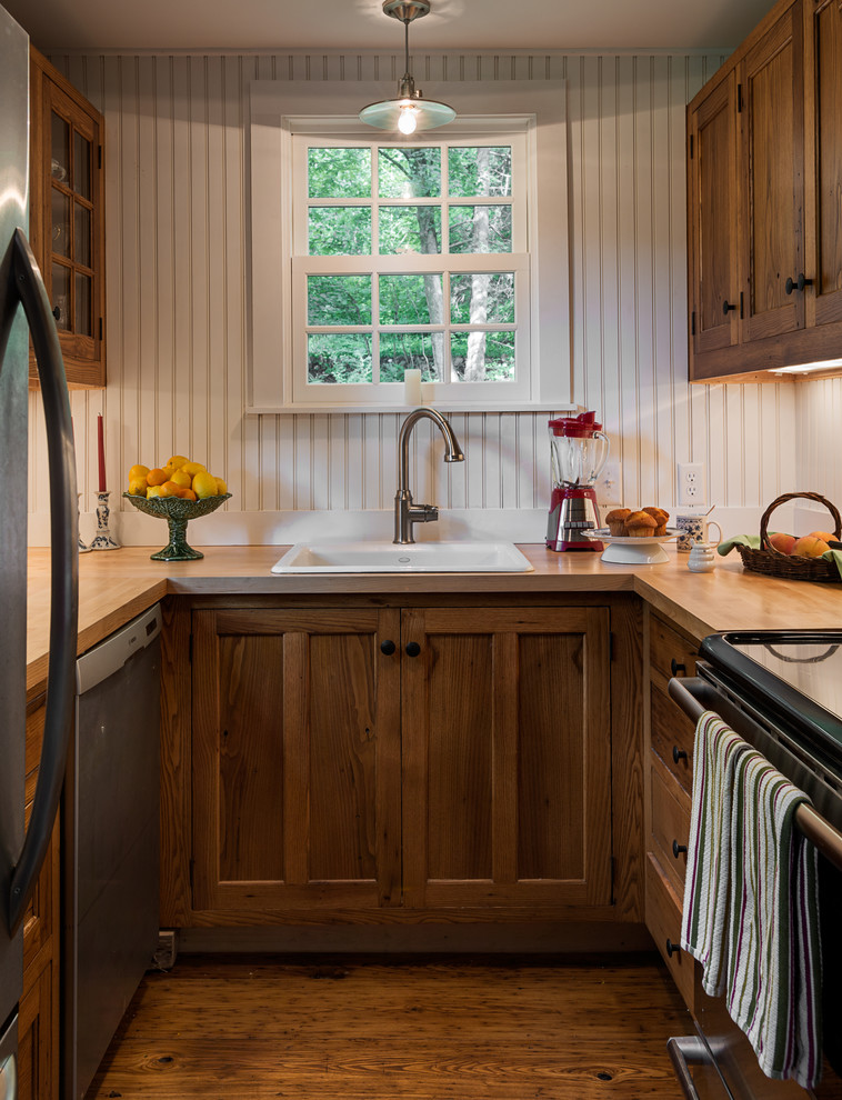 Photo of a small traditional u-shaped separate kitchen in New York with a drop-in sink, recessed-panel cabinets, dark wood cabinets, wood benchtops and stainless steel appliances.