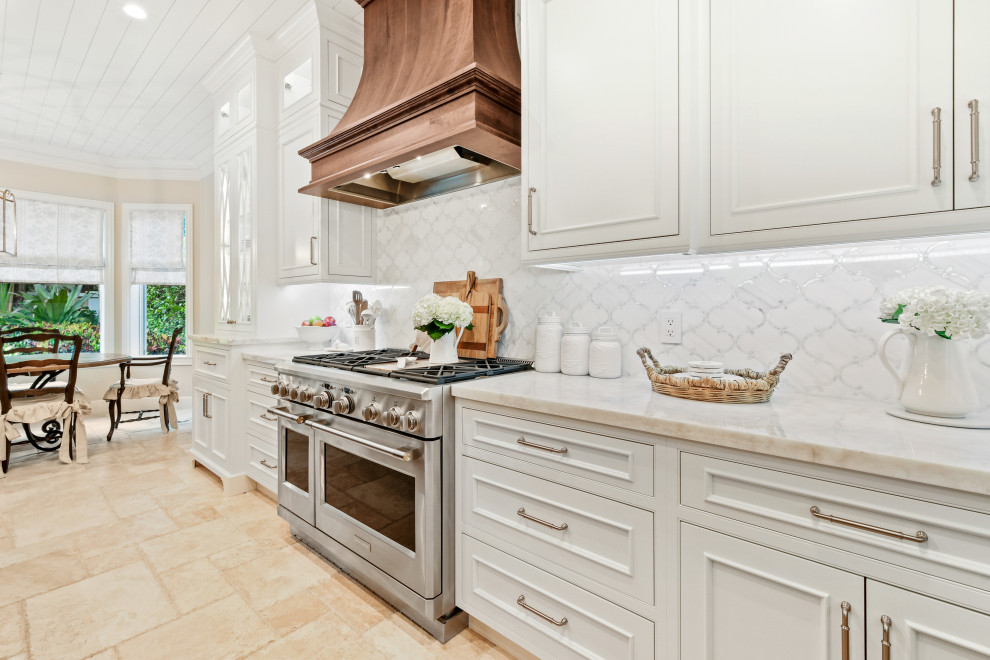 Design ideas for a mid-sized l-shaped open plan kitchen in Other with an undermount sink, beaded inset cabinets, white cabinets, quartzite benchtops, white splashback, marble splashback, panelled appliances, limestone floors, with island, beige floor, white benchtop and wood.
