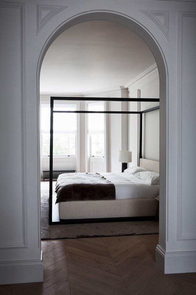 Large contemporary master bedroom in London with white walls and light hardwood floors.