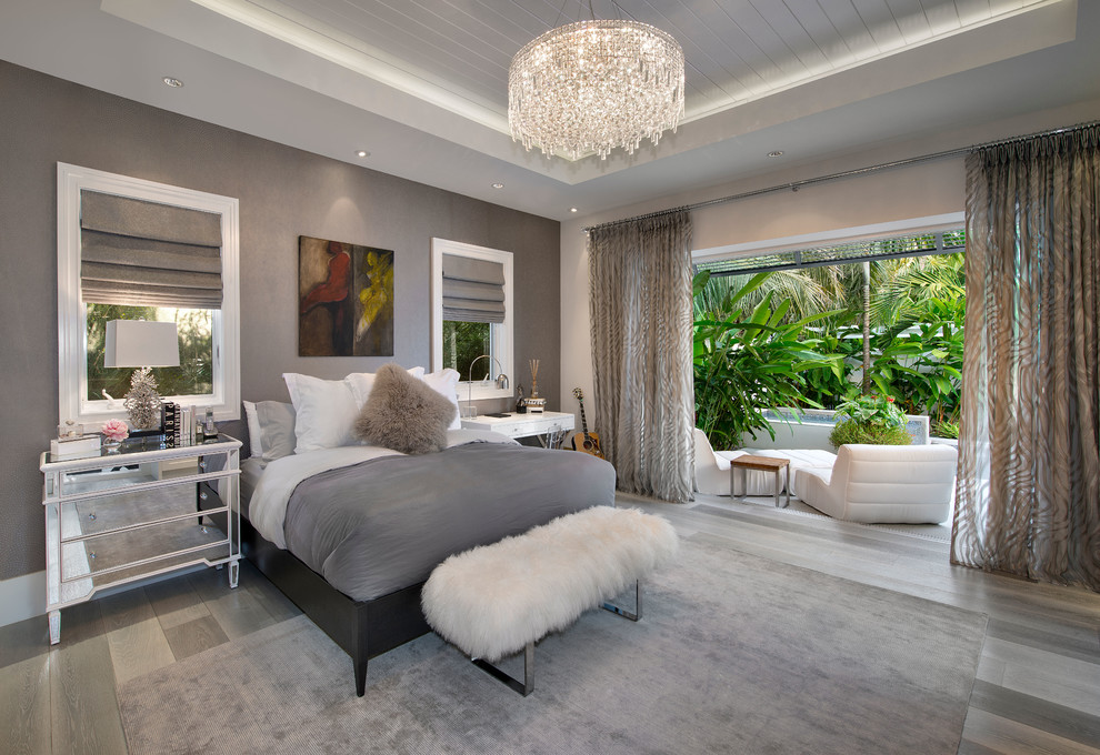 Design ideas for a beach style master bedroom in Miami with grey walls and light hardwood floors.
