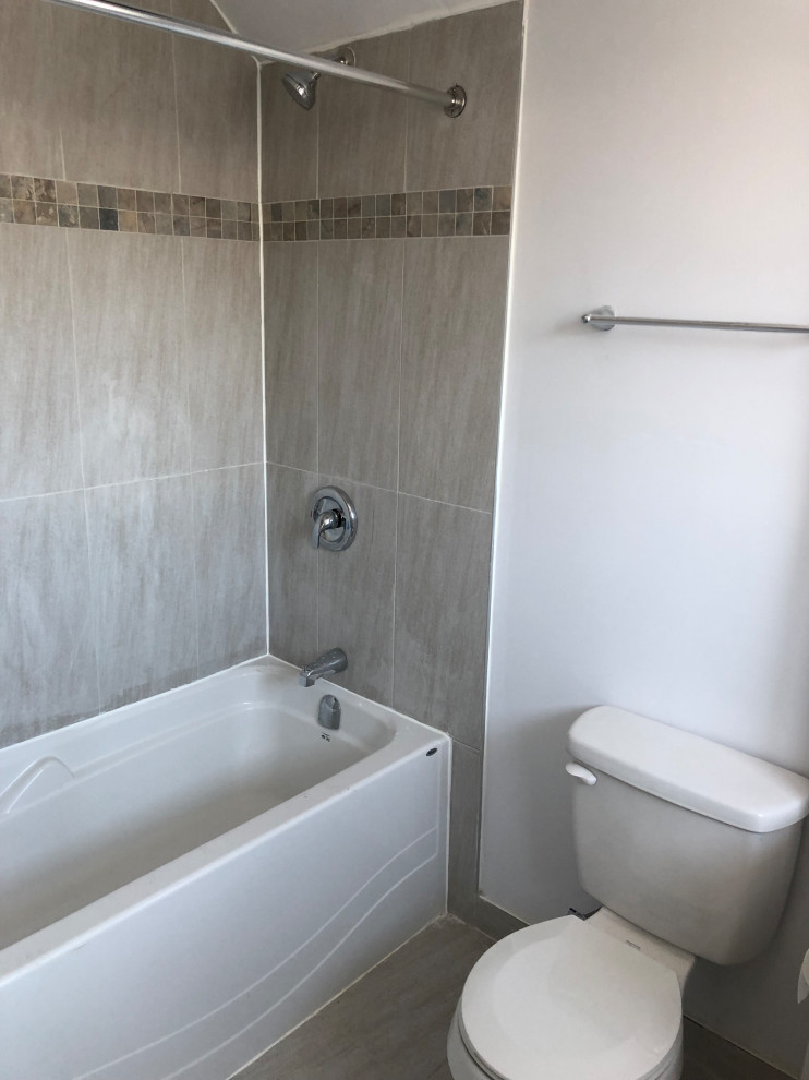 Photo of a small 3/4 bathroom in Ottawa with a corner tub, an open shower, a one-piece toilet, gray tile, porcelain tile, white walls, porcelain floors, white floor and an open shower.