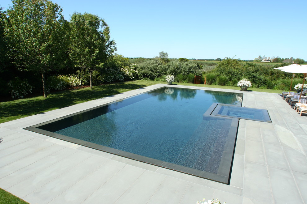 Inspiration for a contemporary custom-shaped infinity pool in New York with natural stone pavers and a hot tub.
