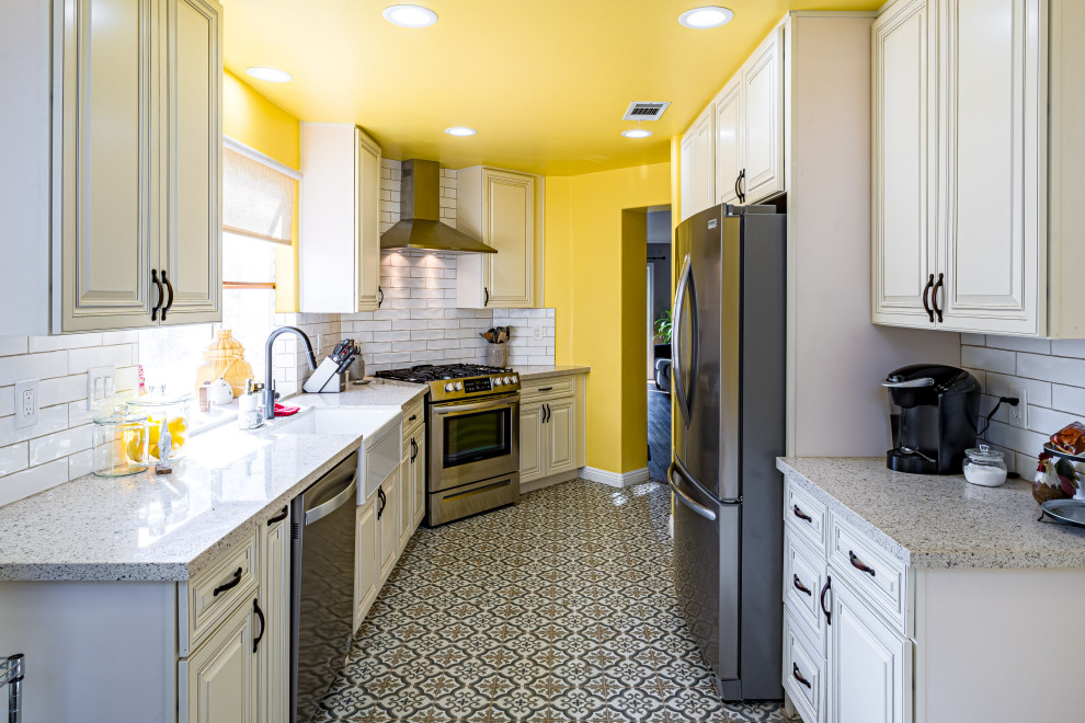 Large country galley eat-in kitchen in Los Angeles with a farmhouse sink, shaker cabinets, beige cabinets, quartz benchtops, white splashback, subway tile splashback, stainless steel appliances, ceramic floors, no island, multi-coloured floor and multi-coloured benchtop.