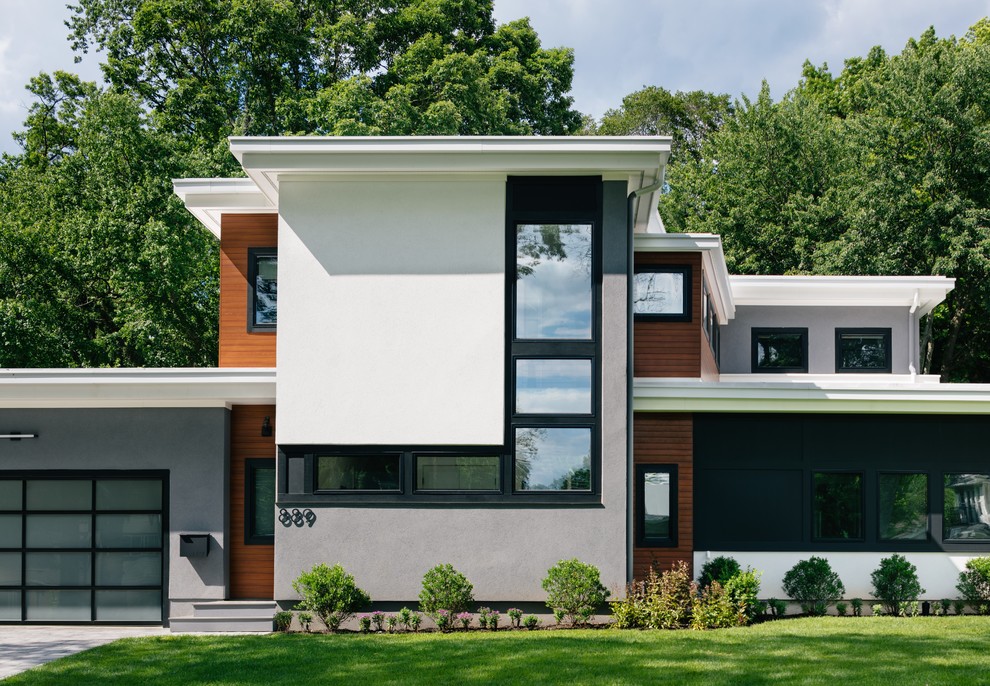 Large contemporary two-storey concrete grey house exterior in New York with a flat roof.