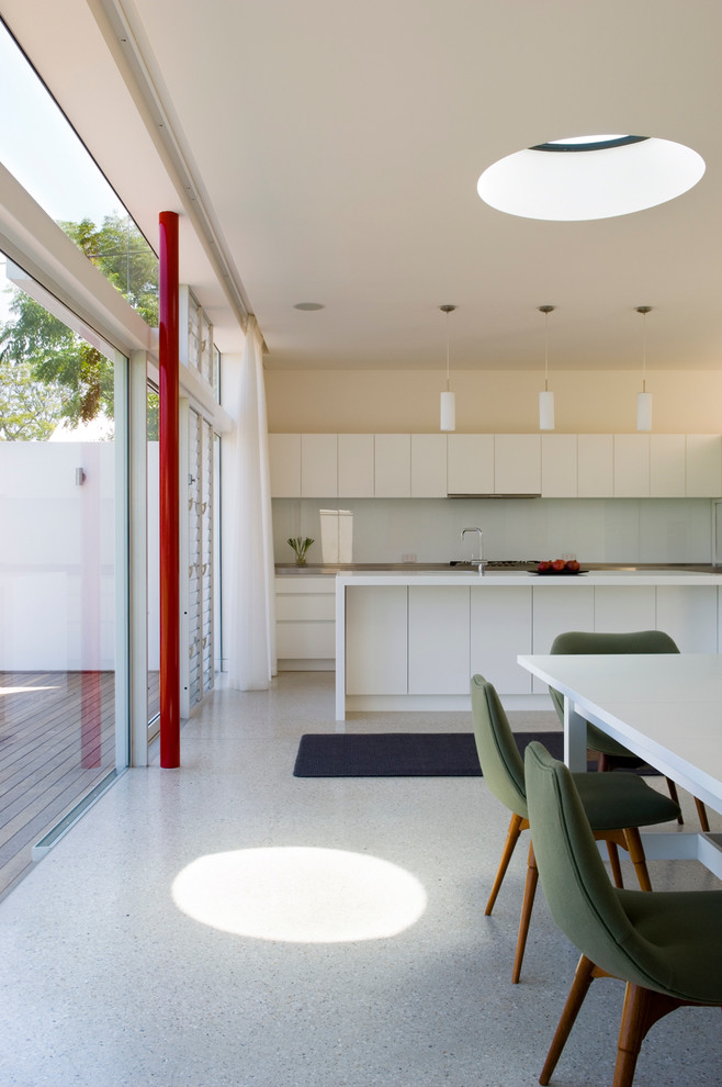 Mid-sized contemporary galley open plan kitchen in Adelaide with an undermount sink, flat-panel cabinets, white cabinets, quartz benchtops, glass sheet splashback, concrete floors and with island.