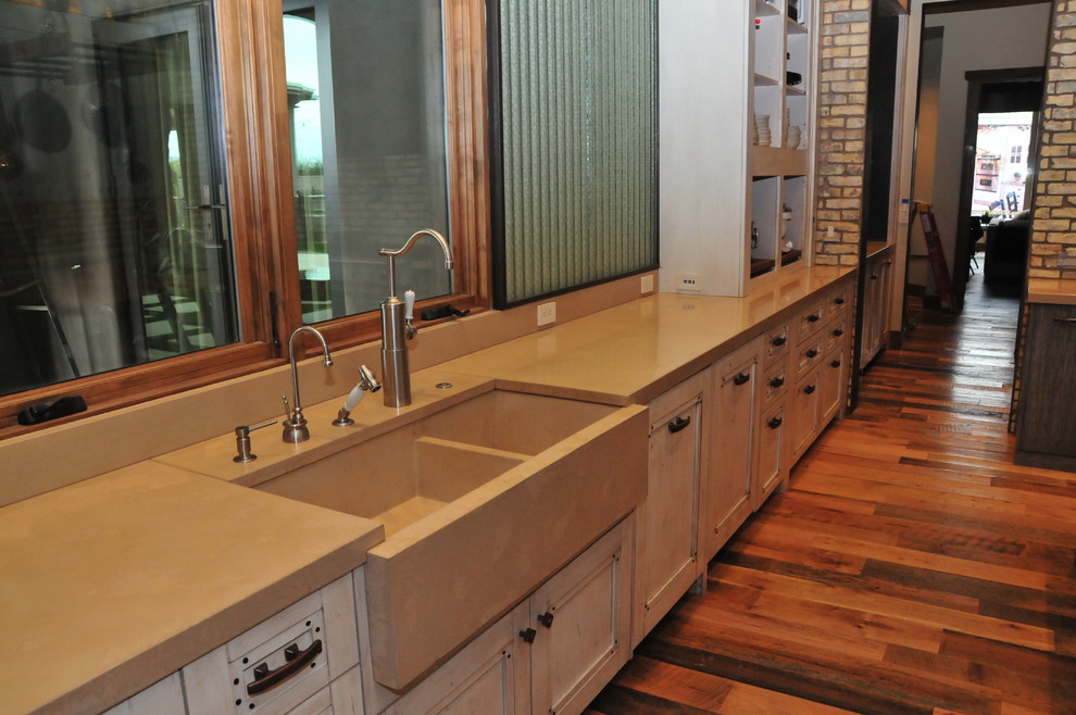 Photo of a large country u-shaped separate kitchen in Phoenix with a farmhouse sink, recessed-panel cabinets, distressed cabinets, concrete benchtops, dark hardwood floors, with island, brown floor and beige benchtop.