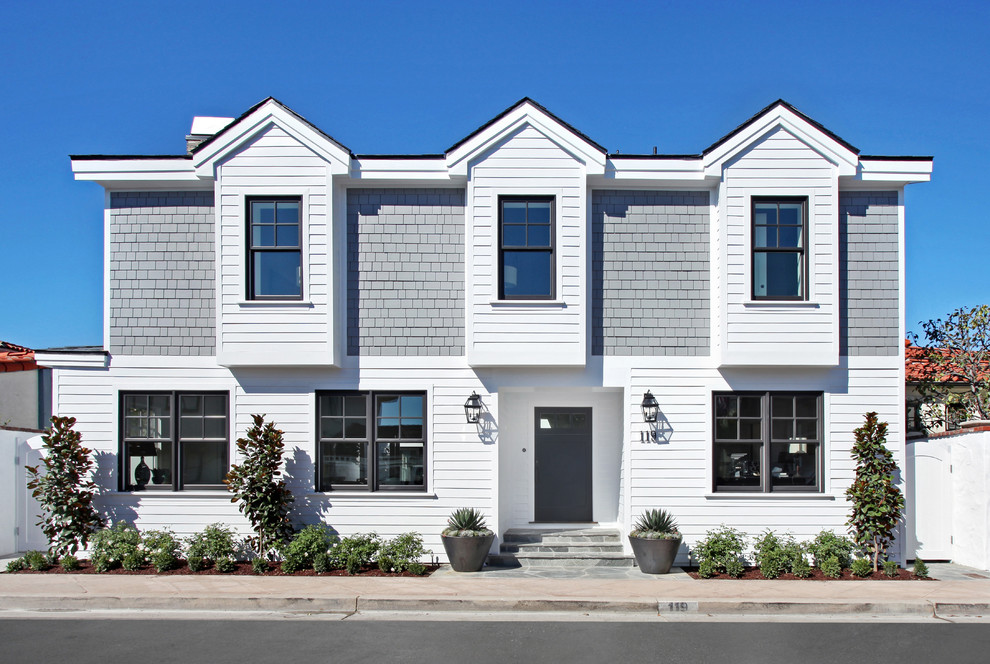 Photo of a beach style two-storey white exterior in Orange County with wood siding.
