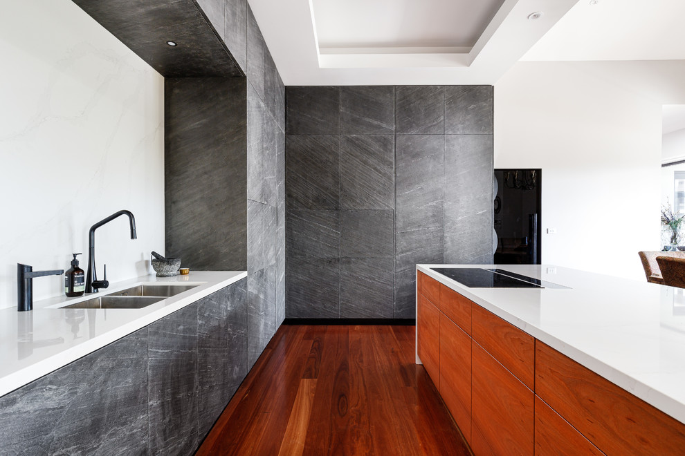 Contemporary l-shaped kitchen in Central Coast with a double-bowl sink, flat-panel cabinets, grey cabinets, white splashback, medium hardwood floors, with island, brown floor and white benchtop.