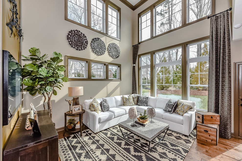 Photo of a small transitional open concept family room in Charlotte with beige walls, light hardwood floors and a wall-mounted tv.
