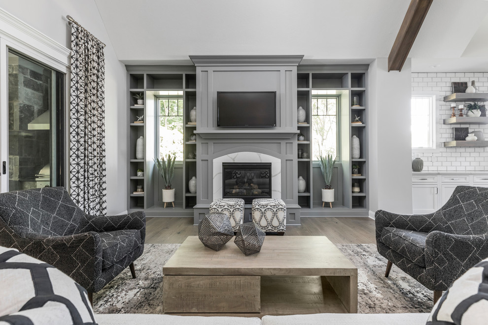 Photo of a mid-sized transitional open concept living room in Indianapolis with grey walls, medium hardwood floors, a standard fireplace and brown floor.
