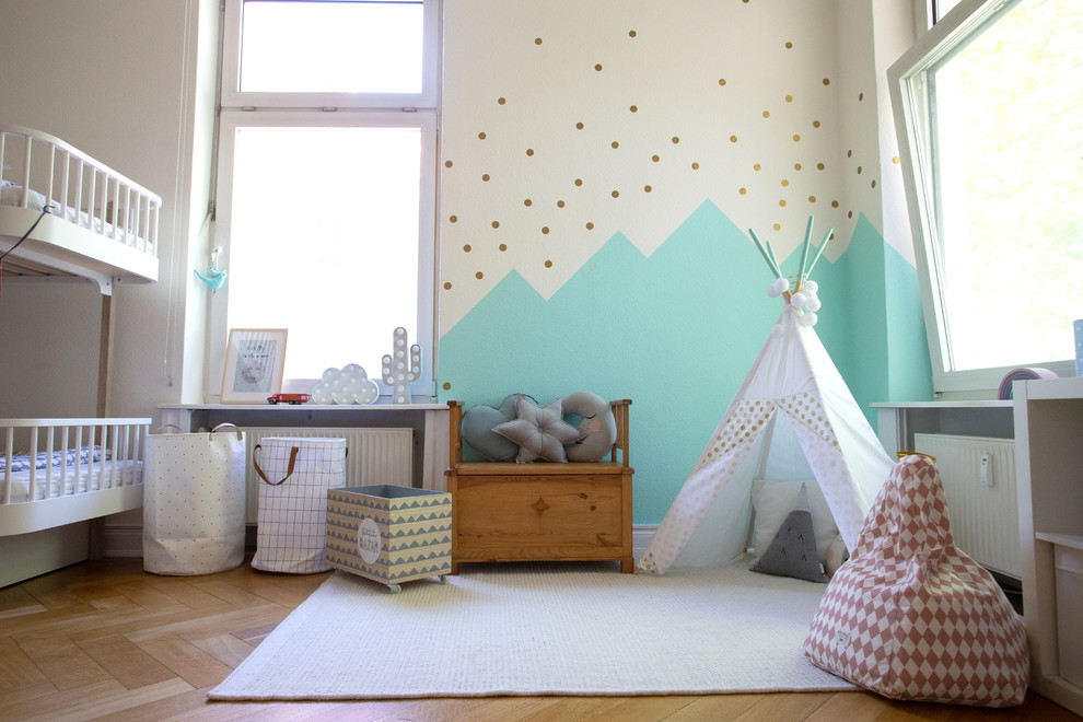 This is an example of a large scandinavian kids' playroom for boys and kids 4-10 years old in Hamburg with white walls, medium hardwood floors and beige floor.