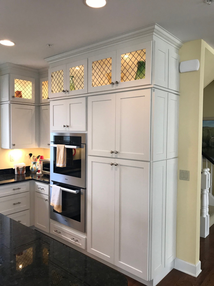 Eat-in kitchen - large craftsman l-shaped dark wood floor and brown floor eat-in kitchen idea with an integrated sink, recessed-panel cabinets, white cabinets, granite countertops, stainless steel appliances, an island and black countertops