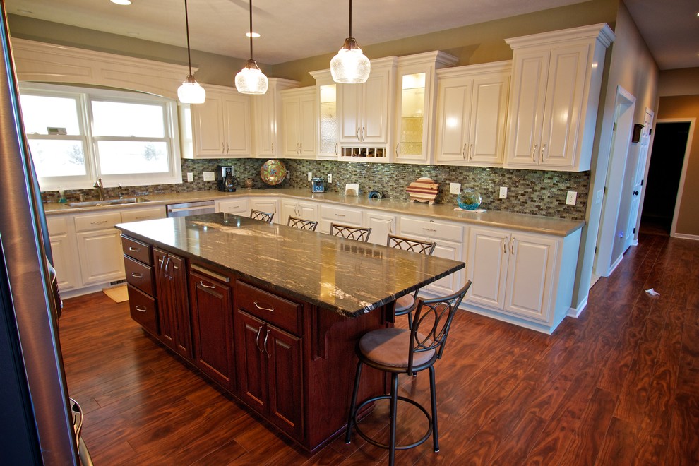 Open concept kitchen - large u-shaped medium tone wood floor open concept kitchen idea with a drop-in sink, raised-panel cabinets, white cabinets, multicolored backsplash, glass tile backsplash, stainless steel appliances and an island