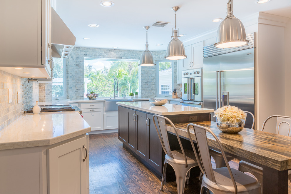 Open concept kitchen - large transitional u-shaped medium tone wood floor open concept kitchen idea in Miami with a farmhouse sink, shaker cabinets, white cabinets, quartz countertops, multicolored backsplash, stone tile backsplash, stainless steel appliances and an island