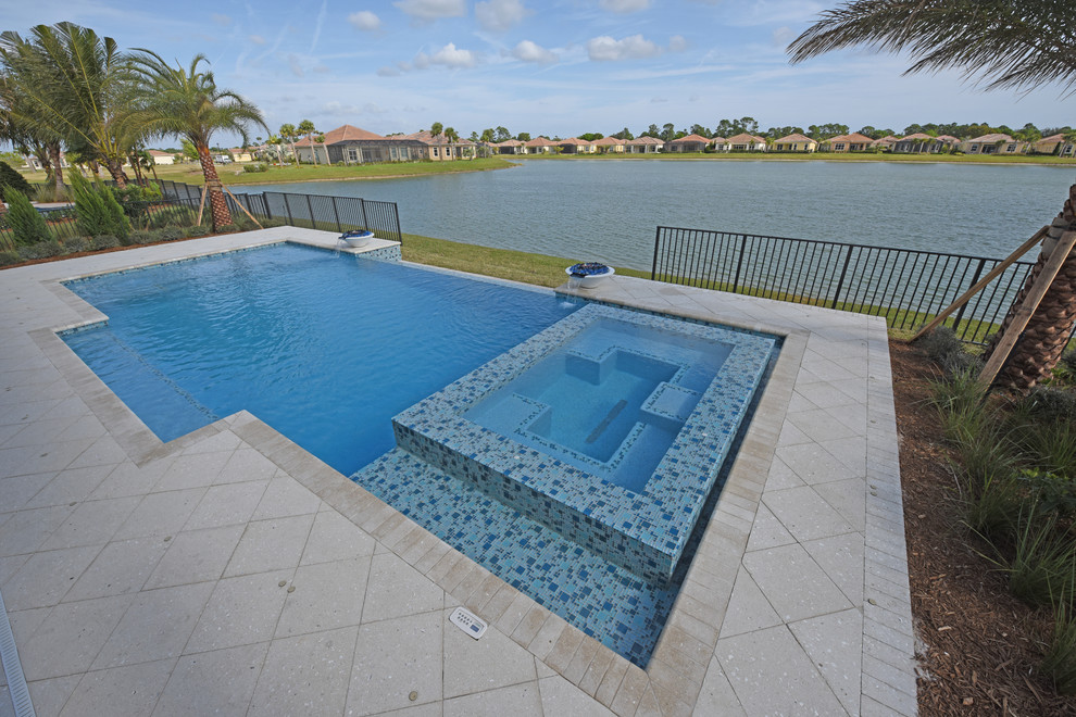 Example of a mid-sized backyard stone and rectangular infinity pool design in Miami