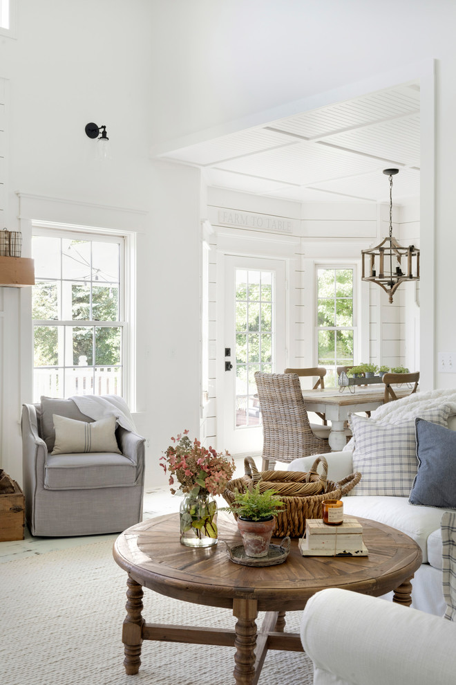 This is an example of a mid-sized country open concept living room in Minneapolis with white walls, painted wood floors, a wood fireplace surround and white floor.