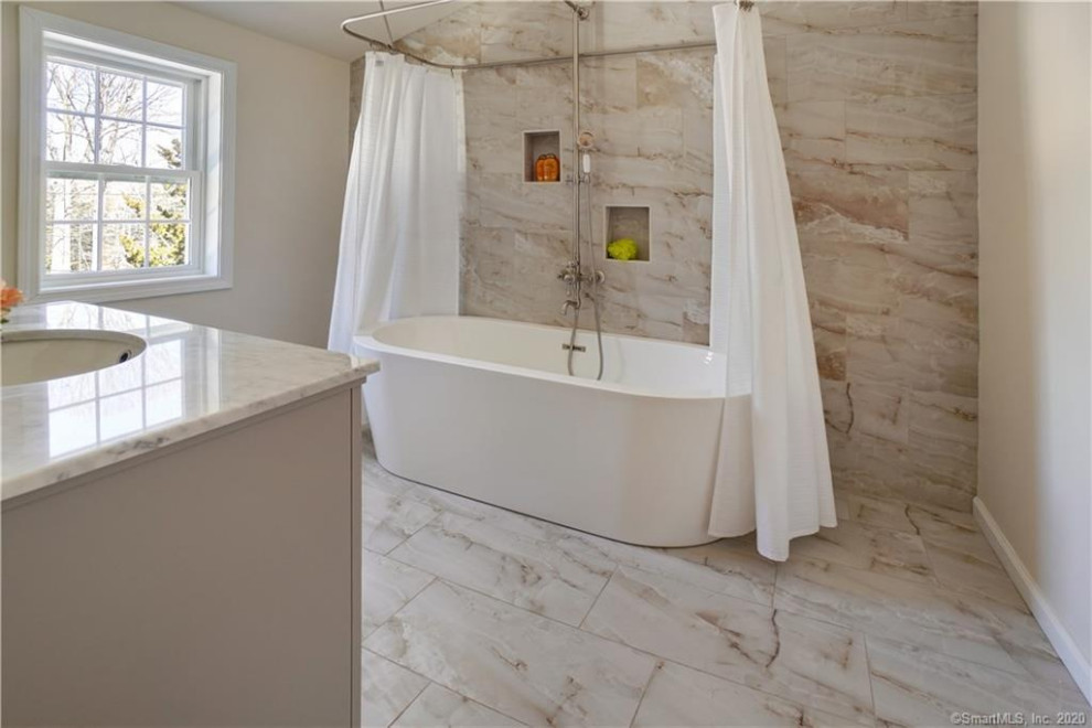 Inspiration for a mid-sized transitional kids bathroom in Other with raised-panel cabinets, grey cabinets, a freestanding tub, a two-piece toilet, beige tile, porcelain tile, beige walls, porcelain floors, an undermount sink, marble benchtops, beige floor, white benchtops, a single vanity and a freestanding vanity.