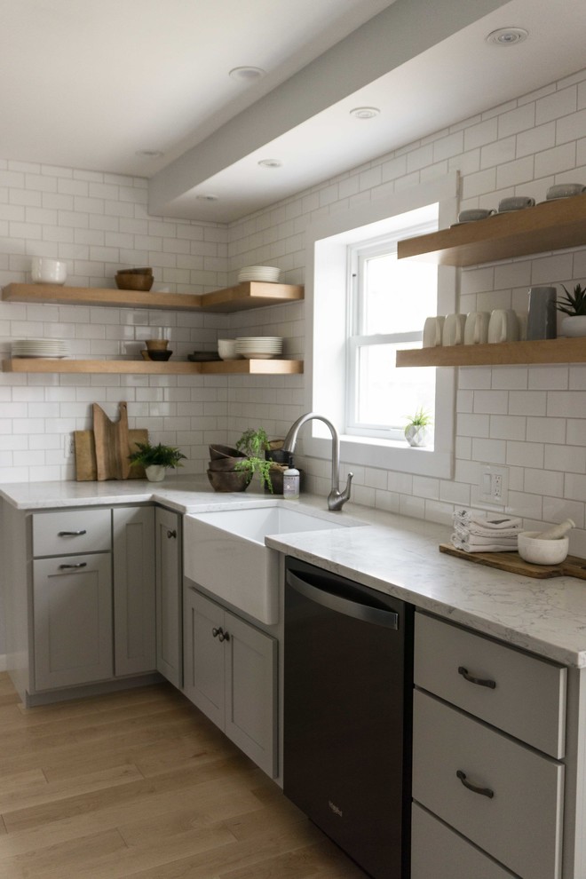 This is an example of a small country eat-in kitchen in Other with a farmhouse sink, shaker cabinets, grey cabinets, quartz benchtops, white splashback, subway tile splashback, stainless steel appliances, light hardwood floors, no island, brown floor and white benchtop.