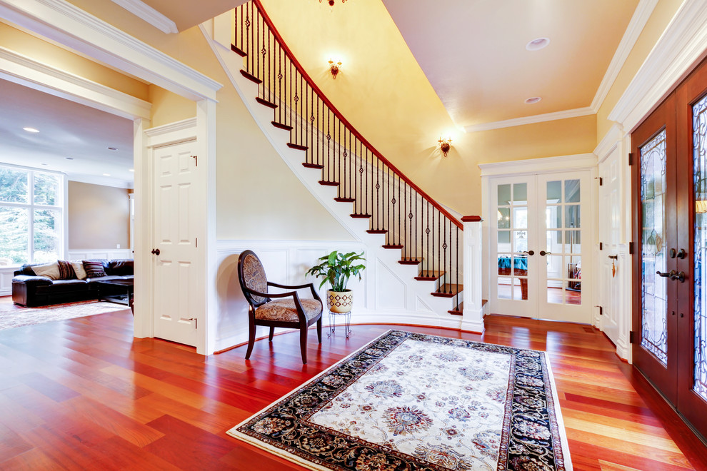 Huge medium tone wood floor foyer photo in Minneapolis with yellow walls and a medium wood front door