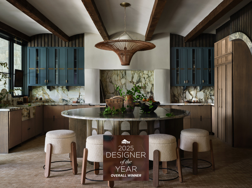 Barrel & Beam - The kitchen at Southlake Manor underwent a full transformation, drawing inspiration from the charm of the South of France while incorporating the Denningtons' personal tastes. A major design feature is the stunning barrelled ceiling, which adds a sense of grandeur and architectural interest. This beautiful ceiling design enhances the space by creating visual height, drawing the eye upward and contributing to the kitchen’s airy and open feel.
The Denningtons’ love for the color blue is woven throughout the kitchen, with custom accents in a rich, deep shade that adds warmth and personality to the space. The cabinetry features a mix of finishes that complement the color palette, creating a balanced, sophisticated look.
At the heart of the kitchen sits a custom, round island—a standout piece designed to be both functional and visually striking. The island, with its unique shape and built-in drawers, provides ample storage while maintaining a sleek, clean aesthetic. It’s an ideal gathering spot for the family and offers a beautiful contrast to the surrounding cabinetry.
The layers of texture throughout the kitchen—from the smooth cabinetry finishes to the intricate details of the island and the natural warmth of the new barrelled ceiling—add depth and dimension. Every element is carefully crafted to elevate the design to the next level, blending style with practicality in a way that reflects the Denningtons' love for sophisticated, yet welcoming spaces.