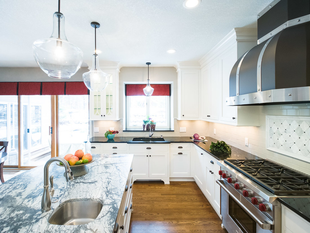 This is an example of a large traditional u-shaped eat-in kitchen in Minneapolis with shaker cabinets, white cabinets, soapstone benchtops, grey splashback, ceramic splashback, stainless steel appliances, medium hardwood floors and with island.