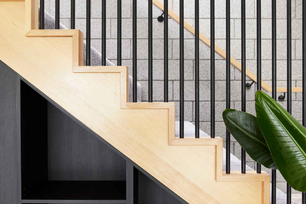 メルボルンにある中くらいなコンテンポラリースタイルのおしゃれなかね折れ階段 (カーペット張りの蹴込み板、木材の手すり、レンガ壁) の写真