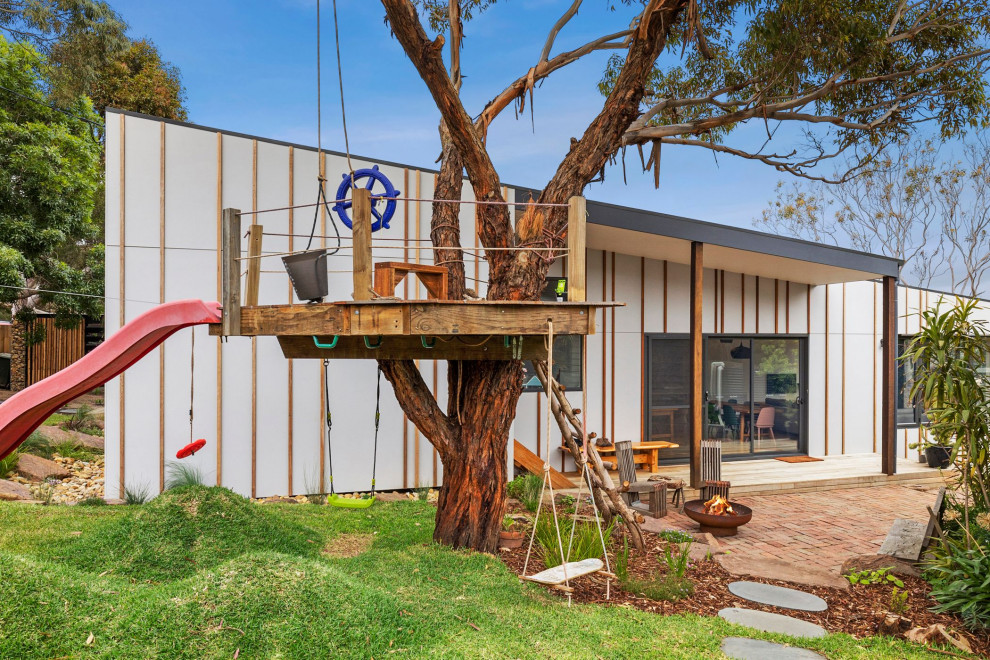Mittelgroßes, Einstöckiges Einfamilienhaus mit Faserzement-Fassade, grauer Fassadenfarbe, Flachdach, Blechdach, weißem Dach und Wandpaneelen in Melbourne