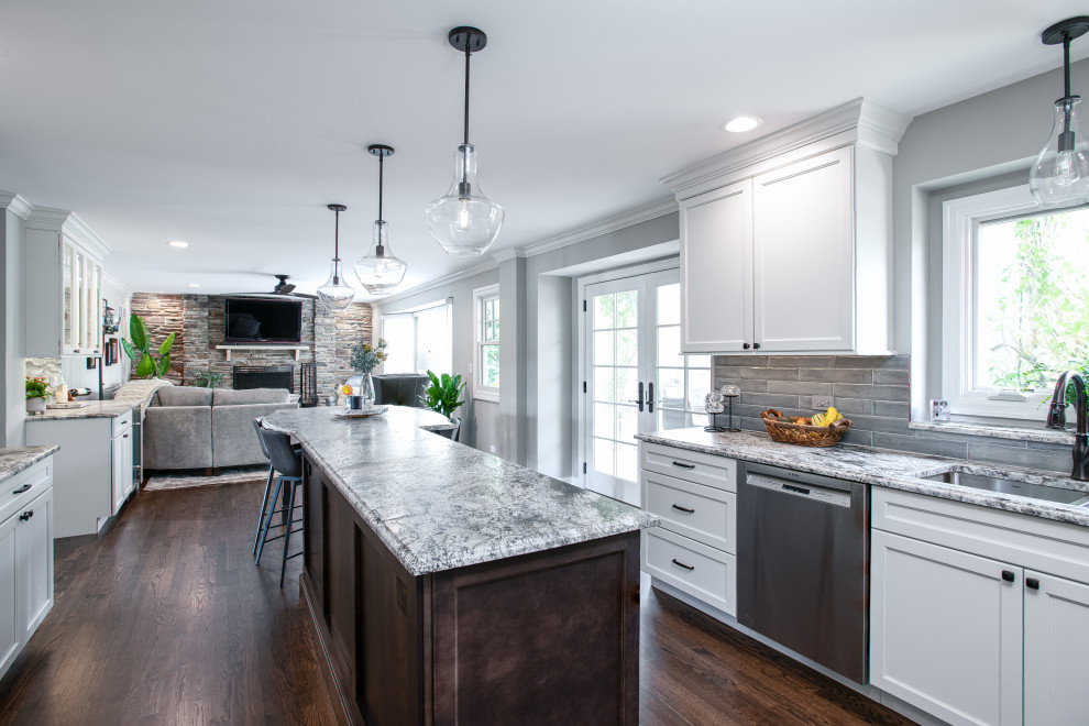 Mid-sized transitional u-shaped dark wood floor and brown floor open concept kitchen photo in Chicago with a double-bowl sink, shaker cabinets, white cabinets, quartz countertops, blue backsplash, porcelain backsplash, stainless steel appliances, an island and gray countertops