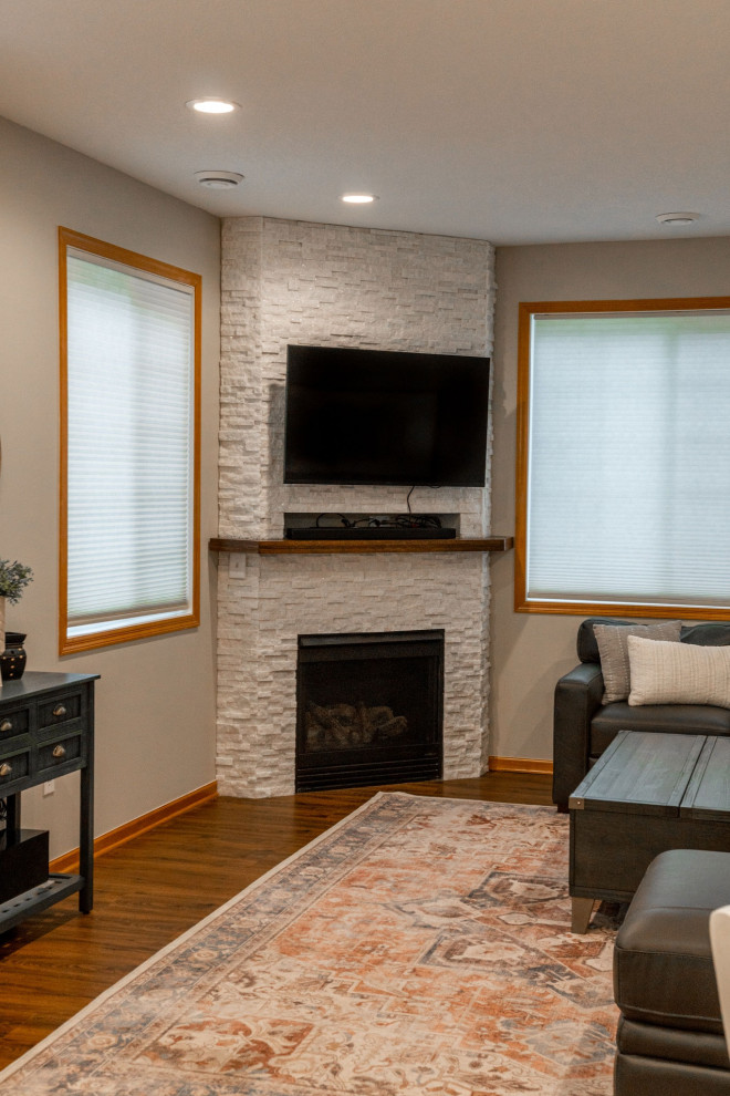 ミネアポリスにある高級な広いトランジショナルスタイルのおしゃれなLDK (グレーの壁、クッションフロア、コーナー設置型暖炉、積石の暖炉まわり、茶色い床) の写真