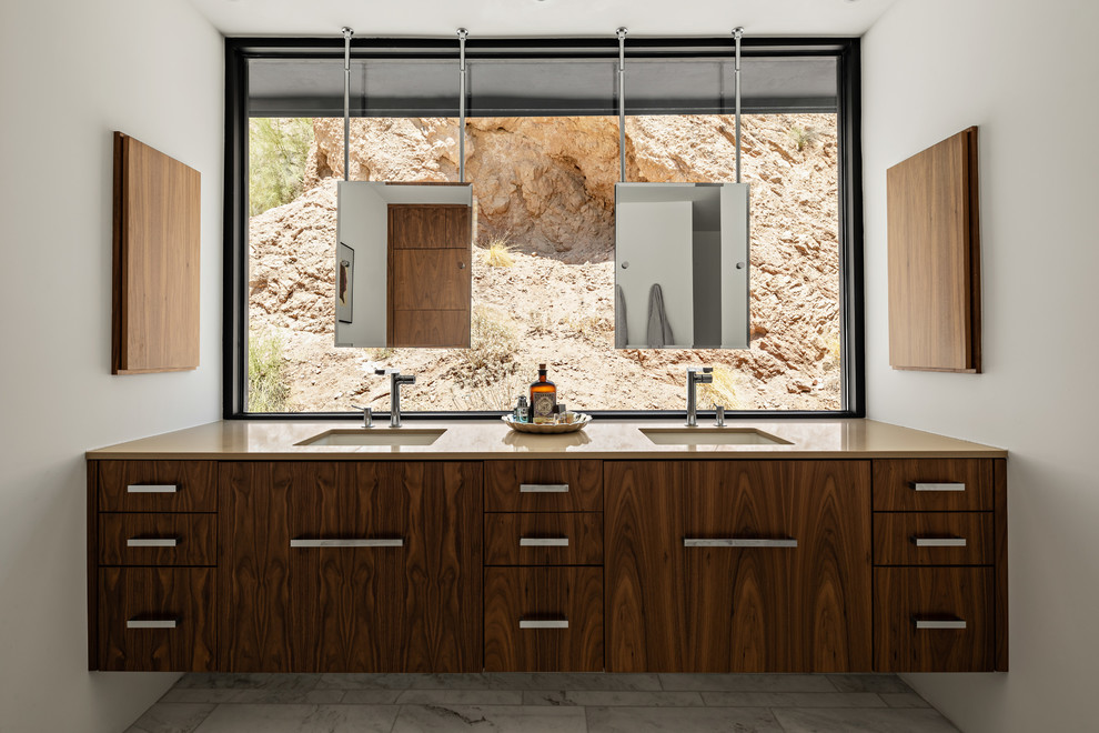 This is an example of a mid-sized contemporary master bathroom in Phoenix with flat-panel cabinets, medium wood cabinets, a double shower, a one-piece toilet, white tile, white walls, marble floors, an undermount sink, engineered quartz benchtops, yellow floor, a hinged shower door and beige benchtops.