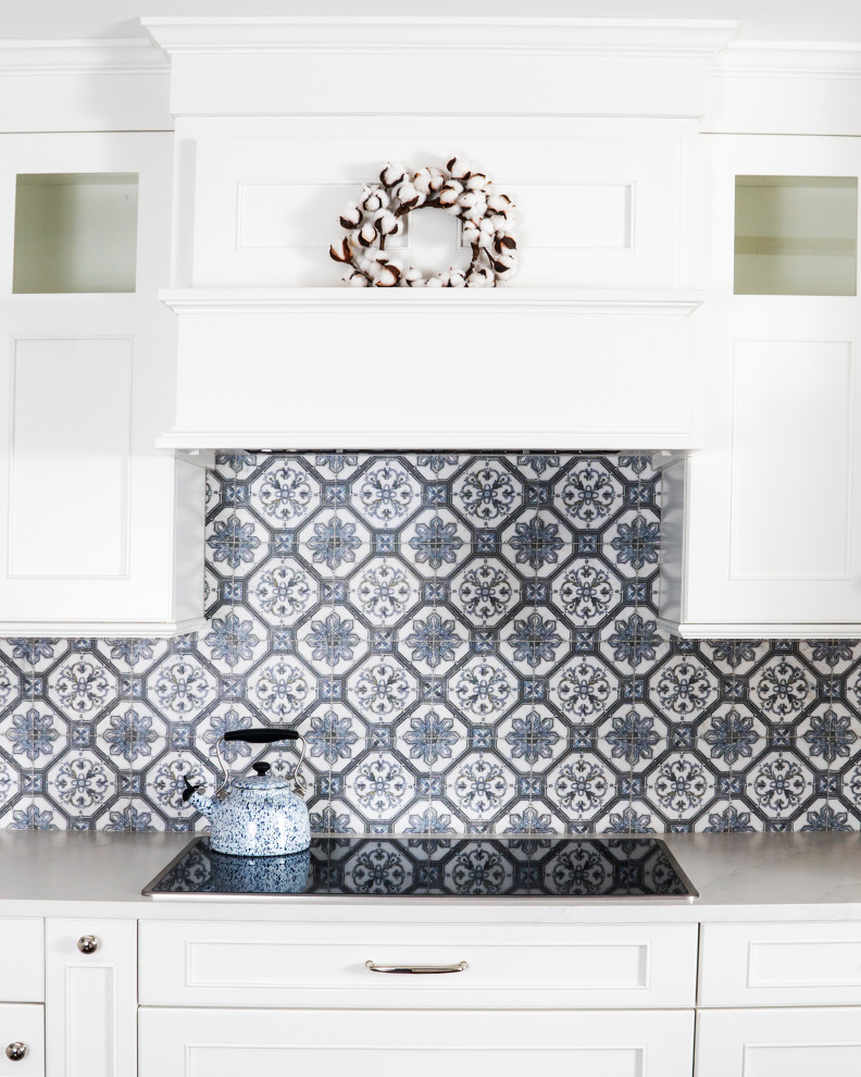 Mid-sized transitional l-shaped medium tone wood floor and brown floor eat-in kitchen photo in St Louis with a farmhouse sink, recessed-panel cabinets, white cabinets, quartz countertops, blue backsplash, ceramic backsplash, stainless steel appliances, an island and white countertops