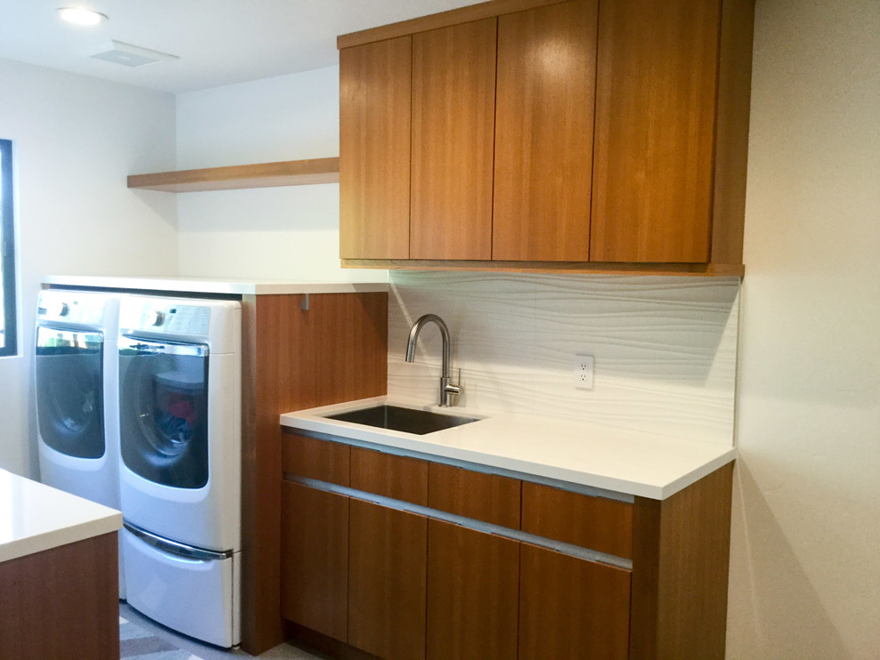 Photo of a mid-sized contemporary galley dedicated laundry room in San Francisco with an undermount sink, flat-panel cabinets, medium wood cabinets, quartz benchtops, white walls, porcelain floors and a side-by-side washer and dryer.